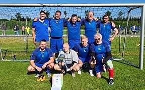 Eine Gruppe von Fußballspielern posiert stolz mit einem Pokal.